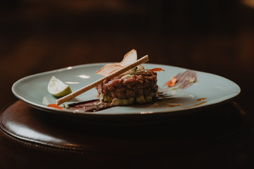 Steak tartar de carne con palillo, y aderezo de lima con salsa de soja en un plato elegante
