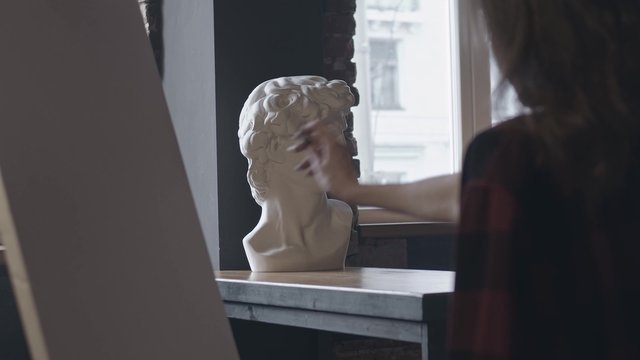 Silhouette of woman measuring proportions of bust with pencil of statue bust, shot in slow motion