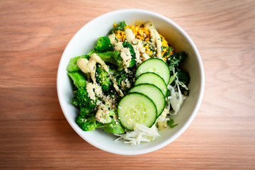 Keto green vegan bowl salad with cucumbers broccoli and tahini salad dressing from a vegetarian restaurant 