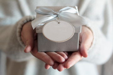 Female hands holding a gift with blank card with copy space