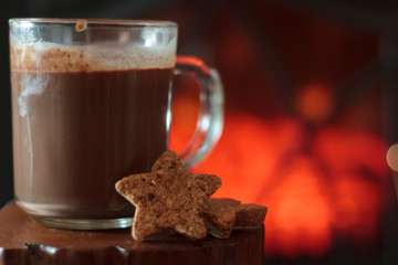 Hot chocolate and cookies with fireplace on the background
