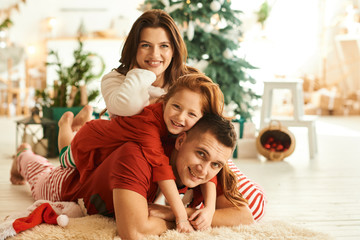 A portrait of happy family in the pajamas in the kitchen on the Christmas tree background