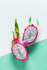 Creative flat layout with dragonfruit (pitaya or pitahaya) on two tone double color paper, white and green mint background. Top view, flat lay of the whole fresh ripe healthy exotic fruit.