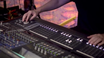 Sound technician mixes audio with sound mixer console across the stage