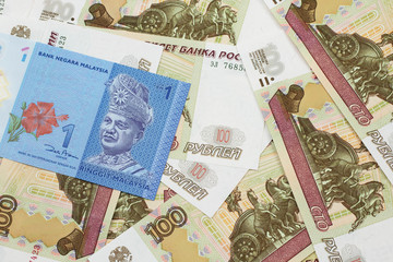 A close up image of a blue one Malaysian ringgit bank note on a bed of Russian one hundred ruble bank notes close up in macro