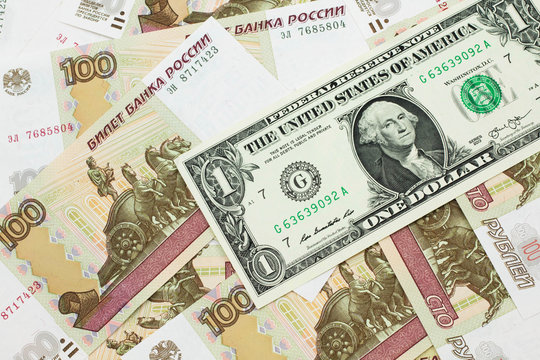 A close up image of a an American one dollar bank note with Russian one hundred ruble bills in macro