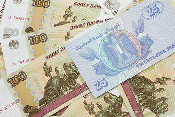 A close up image of an Egyptian twenty five pisatres note with Russian one hundred ruble bills in macro