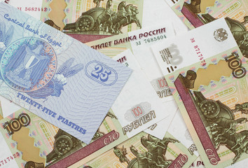 A close up image of an Egyptian twenty five pisatres note with Russian one hundred ruble bills in macro