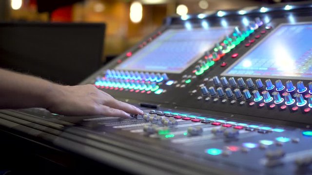 Sound technician mixes audio with sound mixer console across the stage
