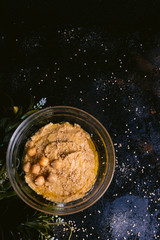 Chickpea hummus with sesame in glass bowl on wooden table. Vegan food