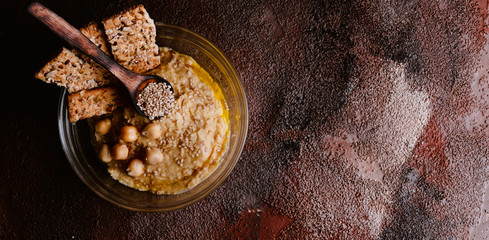 Chickpea hummus with sesame in glass bowl on wooden table. Vegan food