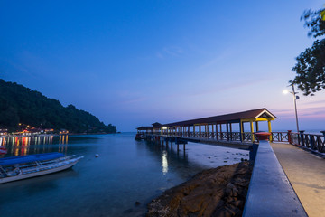 Fototapeta premium Pulau Perhentian, Terengganu - August 14th, 2018 : Beautiful view of small Perhentian Island with multiple boats during blue hour. Image contains noise and soft focus