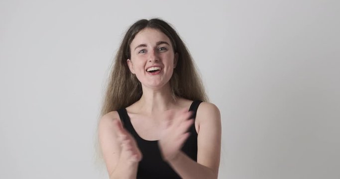 Excited woman clapping hands and praising over white background