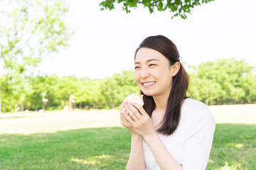 サンドイッチを食べる女性　屋外