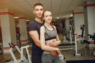 Cute couple standing in a gym. Man and woman in a sportswear.