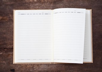 White notebook with lines blurred on wood background.