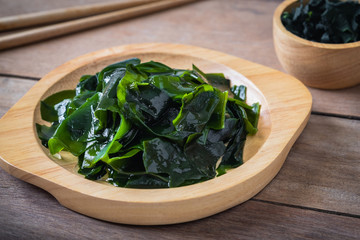 Wakame seaweed on wooden plate and dried seaweed in bowl