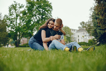 Lovely couple in a summer park. Boy with his girlfriend. Girl with guy sitting on a grass