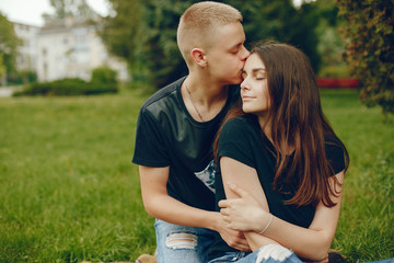 Lovely couple in a summer park. Boy with his girlfriend. Girl with guy sitting on a grass