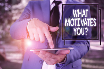 Conceptual hand writing showing What Motivates Youquestion. Concept meaning know reasons why you want to wake up each morning Businessman in blue suite with a tie holds lap top in hands