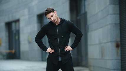 Fit man warming up outdoor in slow motion. Sporty man stretching neck on street