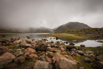 Fog over the lake, before the storm begins in the valley, the humidity causes the moss to grow on the rocks and reflect the mountains on the water