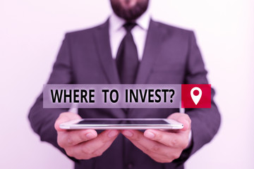 Handwriting text writing Where To Invest Question. Conceptual photo asking about where put money into financial schemes or shares Male human wear formal work suit hold smart hi tech smartphone use
