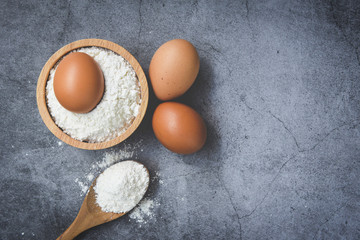 Homemade flour eggs cooking ingredients on kitchen table / Pastry flour on wooden bowl on gray background