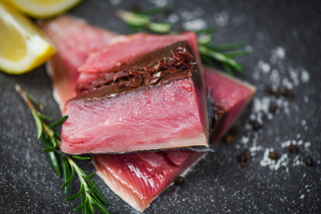 Obraz na płótnie Canvas Fresh fish fillet sliced for steak or salad with herbs spices rosemary and lemon Raw fish seafood on black plate background , Longtail tuna , Eastern little tuna fillet ingredients for cooking food