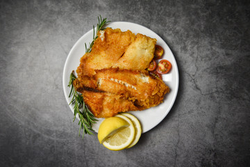 fried fish fillet sliced for steak or salad cooking food with herbs spices rosemary and lemon - tilapia fillet fish crispy served on white plate and dark background