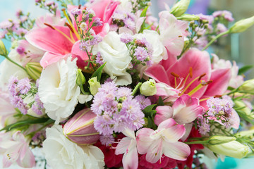 Close up of pink lily flowers around by roses, carnation flowers and green leaves. Close up of beautiful colorful bouquet of flowers with lily and roses. Different kind of flowers. Selective focus.