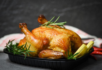 Whole roasted chicken rosemary and tomato lemon on wooden cutting board - Baked chicken grilled barbecue delicious food on dining table at holiday celebrate