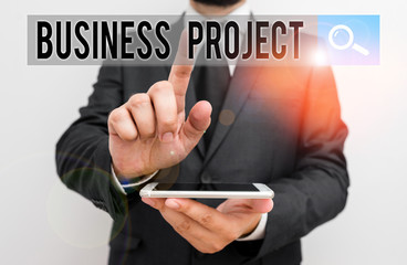 Writing note showing Business Project. Business concept for Planned set of interrelated tasks to be executed over time Male human wear formal work suit hold smartphone using hand