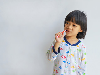 Little boy brushing his teeth copyspace on gray background