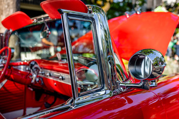 Open bright red vintage retro convertible car with chrome details and moldings exhibited at a...