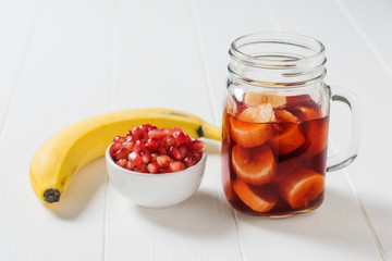 Fresh banana, pomegranate seeds and pomegranate juice in a glass mug.