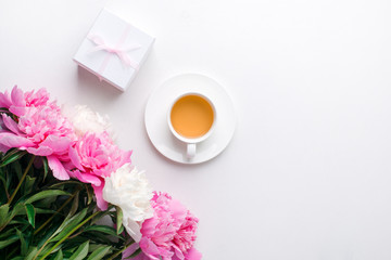 Breakfast for Valentines day with cup of tea, giftbox, flowers on white table from above in flat lay style, seasonal springtime 8 march  holiday background, copy space