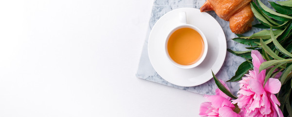 Breakfast for Valentines day with cup of tea, croissant, flowers on white table from above in flat lay style, seasonal springtime holiday background, blogger lifestyle, banner