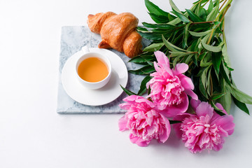 Breakfast for Valentines day with cup of tea, croissant, flowers on white table from above in flat lay style, seasonal springtime holiday background, blogger lifestyle