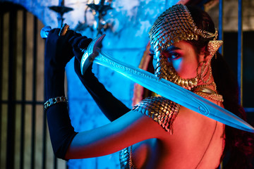 nude art portrait of asian woman in fantasy warrior costume with sword in colorful background