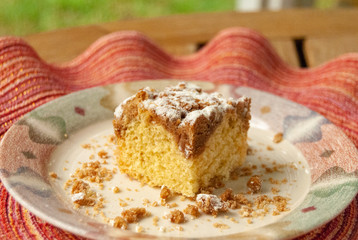 Single piece of coffee crumb cake served on a plate on a colorful pink and red place mat.