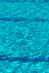 Abstract natural blurred blue background. Pool water texture background. Reflection of sunlight in the pool water. Vertical. The concept of sports and recreation.