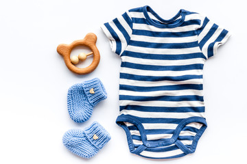 Blue bodysuit for baby boy near children's accessories on white background top-down