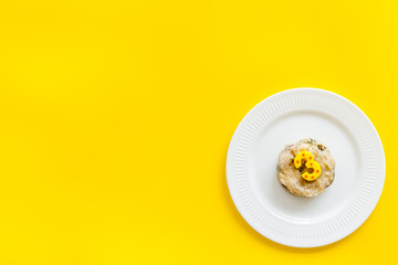 Cat's birthday concept. Pet feed with festive candle in shape of three on yellow background top-down copy space