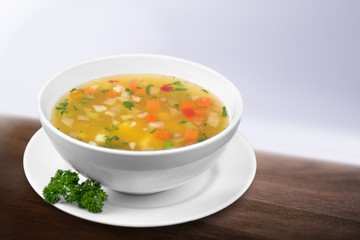 Vegetable soup in white plate on wooden desk