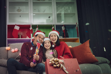 happy family man, woman, little girl play firecracker, firework to celebrate "New Year" together at christmas day night in room that decorated with christmas tree for Asian christmas festival day