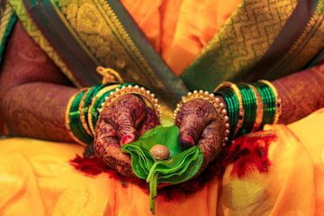 Indian wedding ceremony : Bridal holding green leaf and nut in hand 