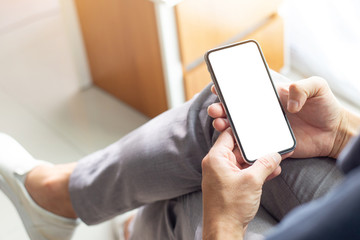 Mockup image blank white screen cell phone.men hand holding texting using mobile on sofa at home office.background empty space for advertise text.people contact marketing business and technology 