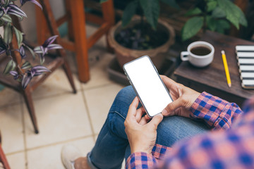 Obraz premium Mockup image blank white screen cell phone.men hand holding texting using mobile on desk at home office.background empty space for advertise text.people contact marketing business and technology 