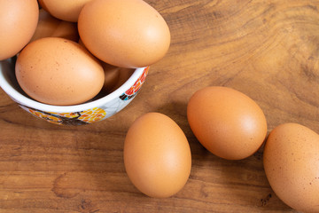 There are many fresh eggs in the picture, placed in cups and on wooden floors.